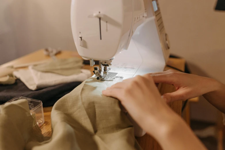 a person using a sewing machine on a table, wearing a linen shirt, foliage clothing, performing, metal readymade