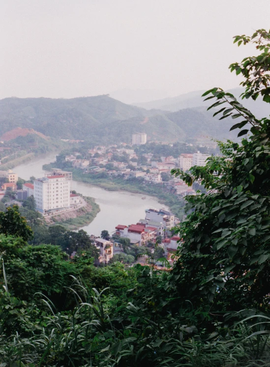 a view of a city from the top of a hill, by Daniel Lieske, trending on unsplash, sumatraism, mountains river trees, photo taken on fujifilm superia, dang my linh, slide show