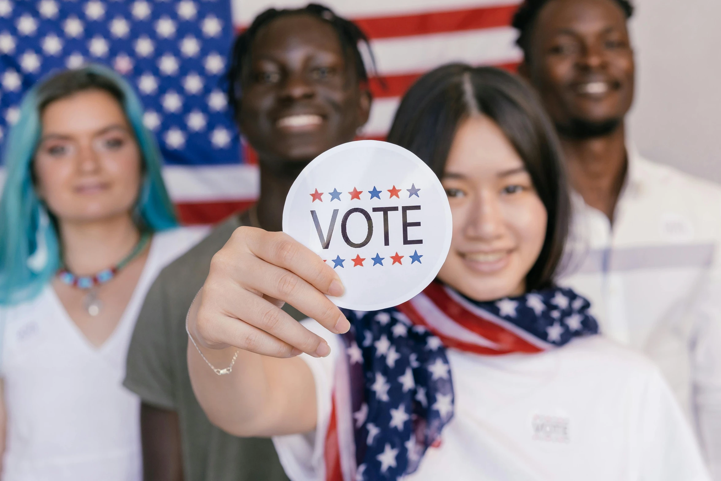 a group of people holding up a vote sign, a photo, trending on pexels, american dream, avatar image, ethnic group, photo of a beautiful