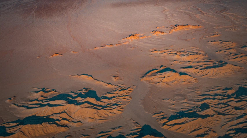 an aerial view of a mountain range at sunset, inspired by Filip Hodas, unsplash contest winner, tonalism, flowing salmon-colored silk, extremely detailed sand, nasa photos, seafloor