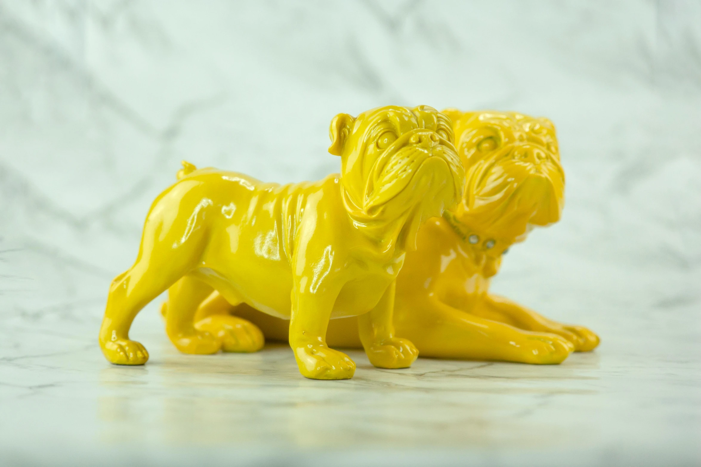 a yellow figurine of a dog on a table, an art deco sculpture, inspired by Jeff Koons, unsplash, laying on their back, two dogs, wrinkly, gloss finish