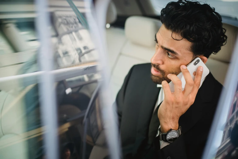 a man sitting in a car talking on a cell phone, man in black suit, kyza saleem, professionally taken, **cinematic
