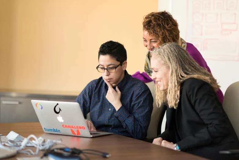 a group of people sitting around a table looking at a laptop, profile image, carlos huante, professional image, non-binary