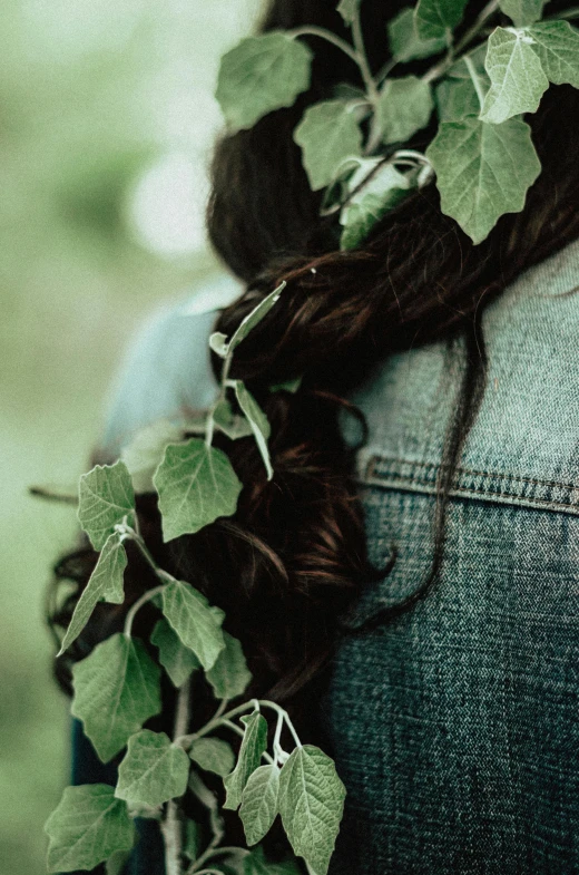 a woman with a flower in her hair, an album cover, inspired by Elsa Bleda, pexels contest winner, overgrown with lush vines, back - shot, loosely cropped, datura