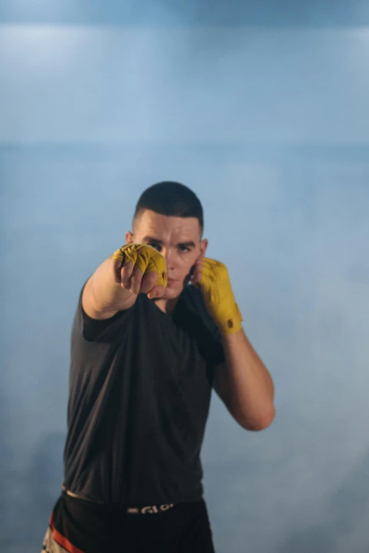 a man in a black shirt and yellow gloves, inspired by Ma Quan, unsplash, realism, buzz cut, fire punch, still from a music video, performance