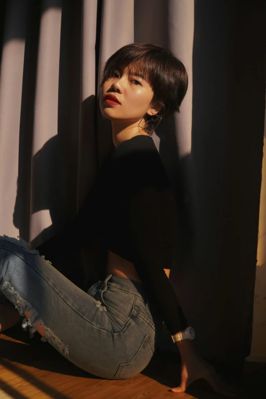 a woman sitting on the floor in front of a window, by Jang Seung-eop, trending on pexels, black short curtain haircut, promotional image, concert photo, wearing a crop top
