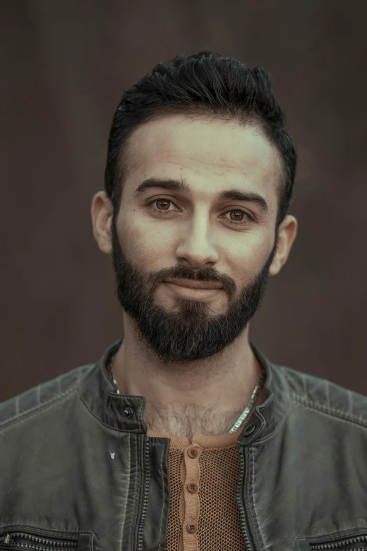 a man with a beard and a leather jacket, pexels contest winner, photorealism, clear julian lage face, androgynous person, desaturated, middle eastern skin