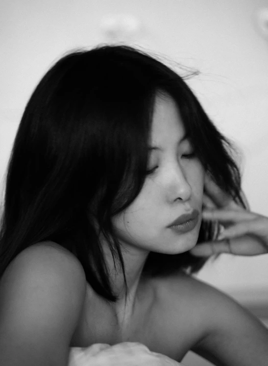 a black and white photo of a woman laying in bed, inspired by Xia Shuwen, profile picture, pout, long thin black hair, flirtatious and intrigued