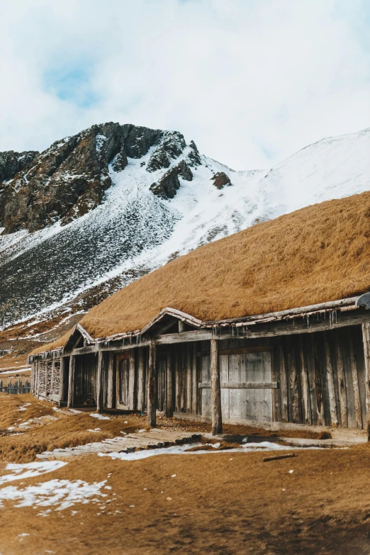 a group of wooden buildings sitting on top of a snow covered mountain, a matte painting, inspired by Peter Zumthor, pexels contest winner, turf roof, rusted walls, autumn, norse