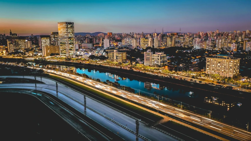 an aerial view of a city at night, by Felipe Seade, pexels contest winner, visual art, oscar niemeyer, golden and blue hour, skyline showing from the windows, all buildings on bridge