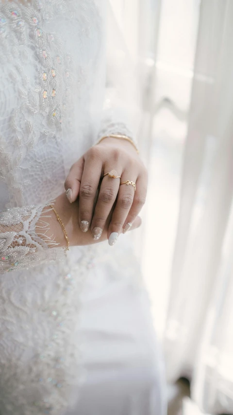 a close up of a person holding a wedding ring, by Basuki Abdullah, pexels, white regal gown, 15081959 21121991 01012000 4k, thumbnail, white and gold dress