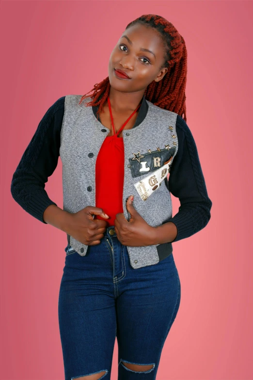 a woman standing in front of a pink background, an album cover, by Ella Guru, cg society contest winner, wearing a jeans jackets, made of felt and cloth and beads, red sweater and gray pants, model is wearing techtical vest