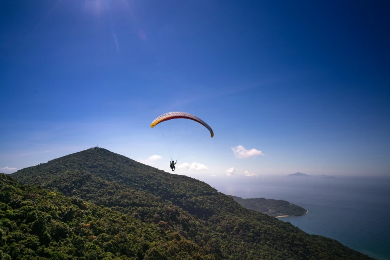 a paraglider flying over a lush green hillside, pexels contest winner, hurufiyya, avatar image, hong kong, seaview, brown