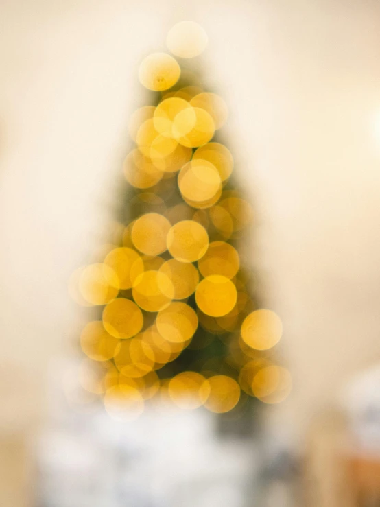 a blurry image of a christmas tree in a living room, unsplash, light and space, yellow aureole, background image, close up portrait shot, shot on sony a 7