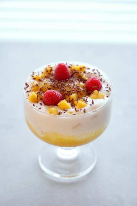 a dessert sitting on top of a table, mango, sea of parfait, booze, raspberry