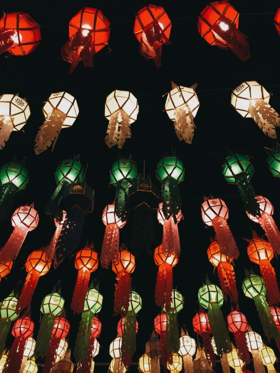 a bunch of paper lanterns hanging from the ceiling, a screenshot, pexels contest winner, baroque, colours red and green, at night, tall, seen from below