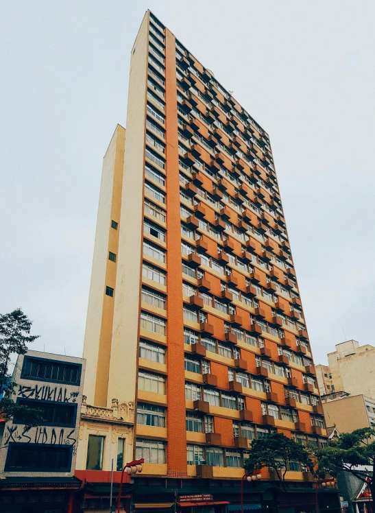 a tall building sitting on the side of a street, by Samuel Silva, unsplash, brutalism, in sao paulo, 🪔 🎨;🌞🌄, orange, 15081959 21121991 01012000 4k