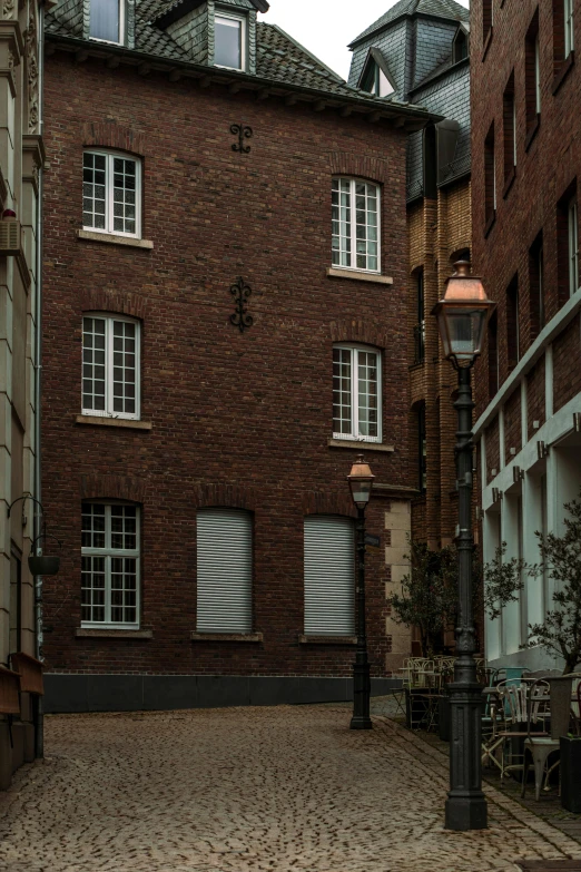 a couple of buildings that are next to each other, a photo, by Daniel Seghers, renaissance, one single gas lamp, red bricks, courtyard, muted colors. ue 5