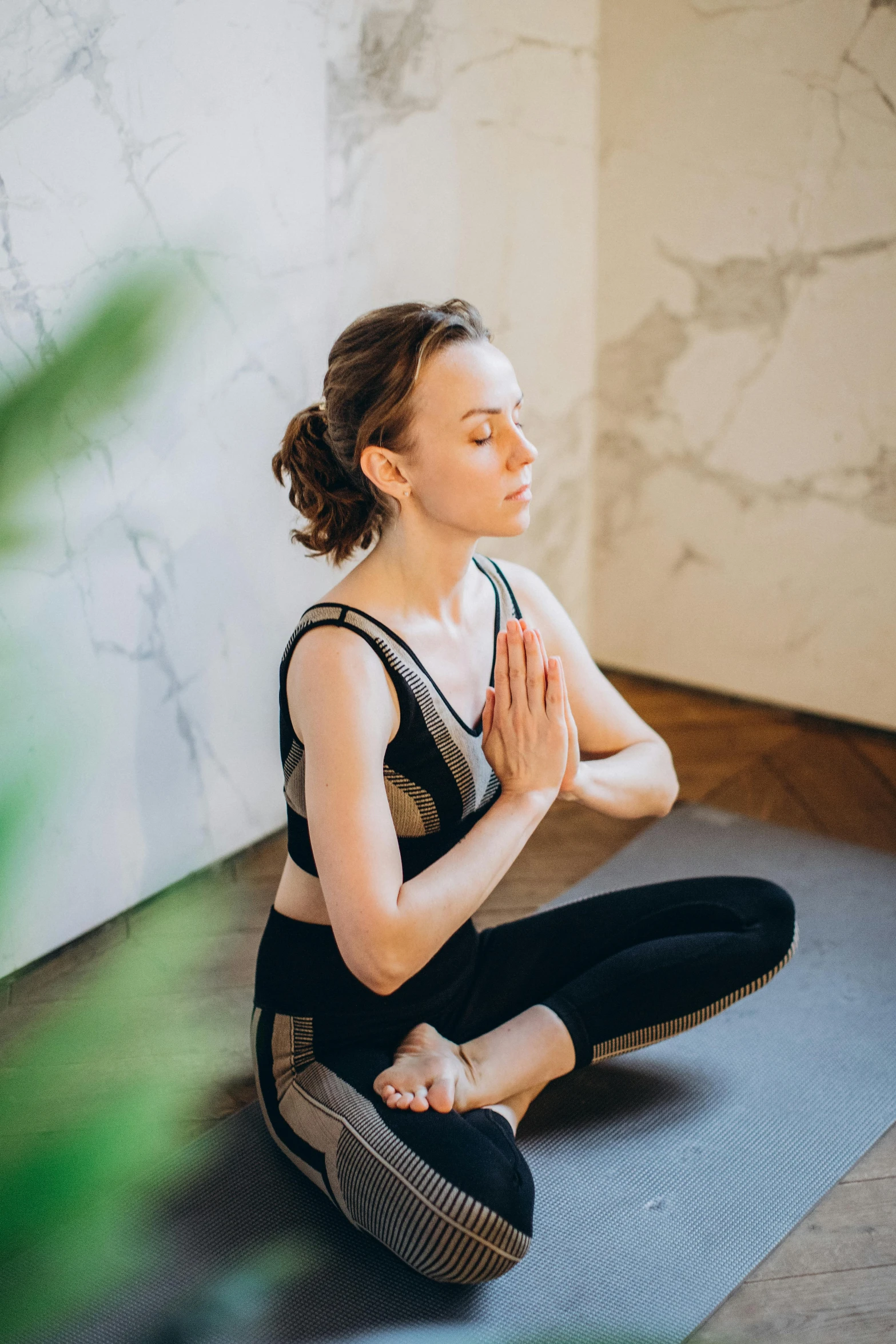 a woman sitting on a yoga mat in the middle of a room, praying posture, promo image, ewa juszkiewicz, low quality photo