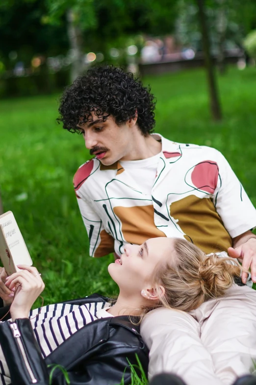 a couple of people that are laying in the grass, trending on pexels, magic realism, julia garner, holding a book, with mustache, azamat khairov