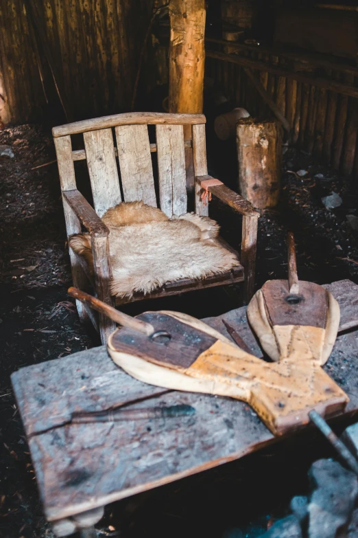 a couple of chairs sitting on top of a wooden table, with an axe, inside a shed