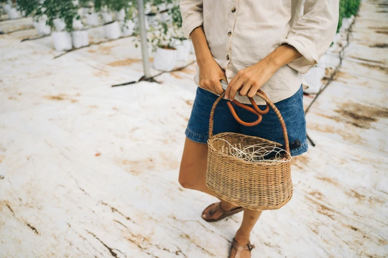 a woman holding a wicker basket in the snow, by Nina Hamnett, pexels contest winner, wearing a camisole and shorts, the handbag is over a wood table, wearing a linen shirt, top down view