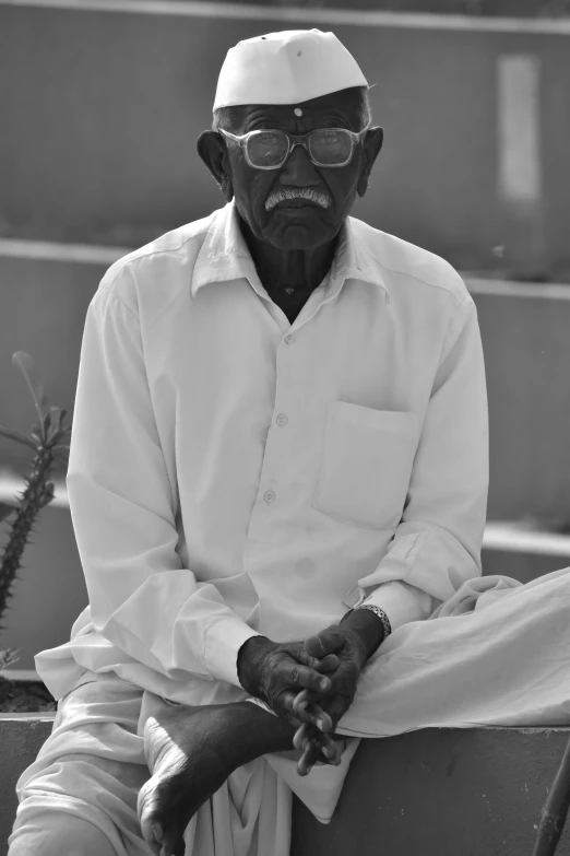 a black and white photo of a man sitting on a bench, a black and white photo, by Bapu, white wrinkled shirt, an all white human, dressed senobith, portrait of a old