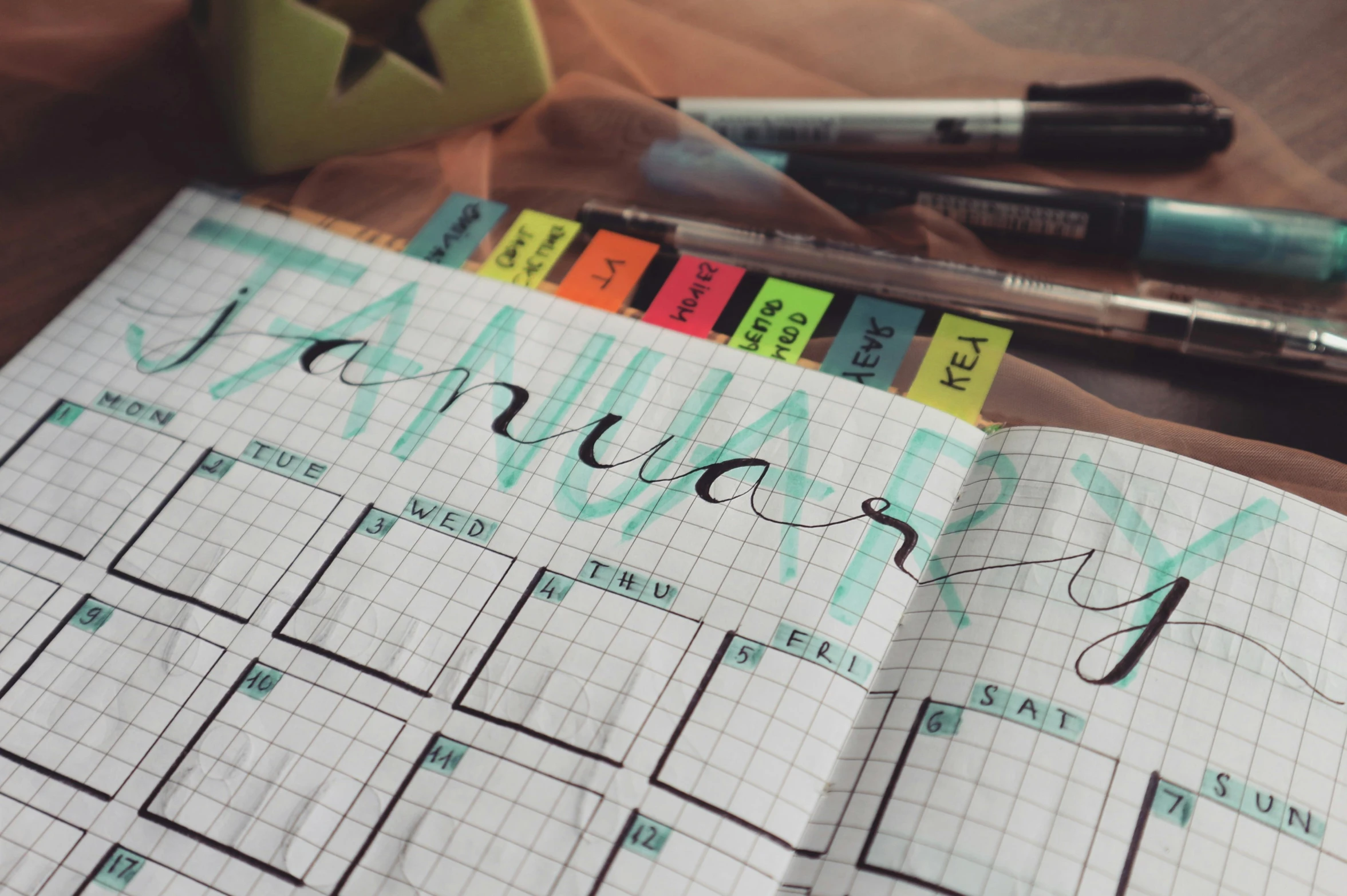 a calendar sitting on top of a wooden table, by Emma Andijewska, trending on pexels, happening, sharpie, knolling, wintertime, performing