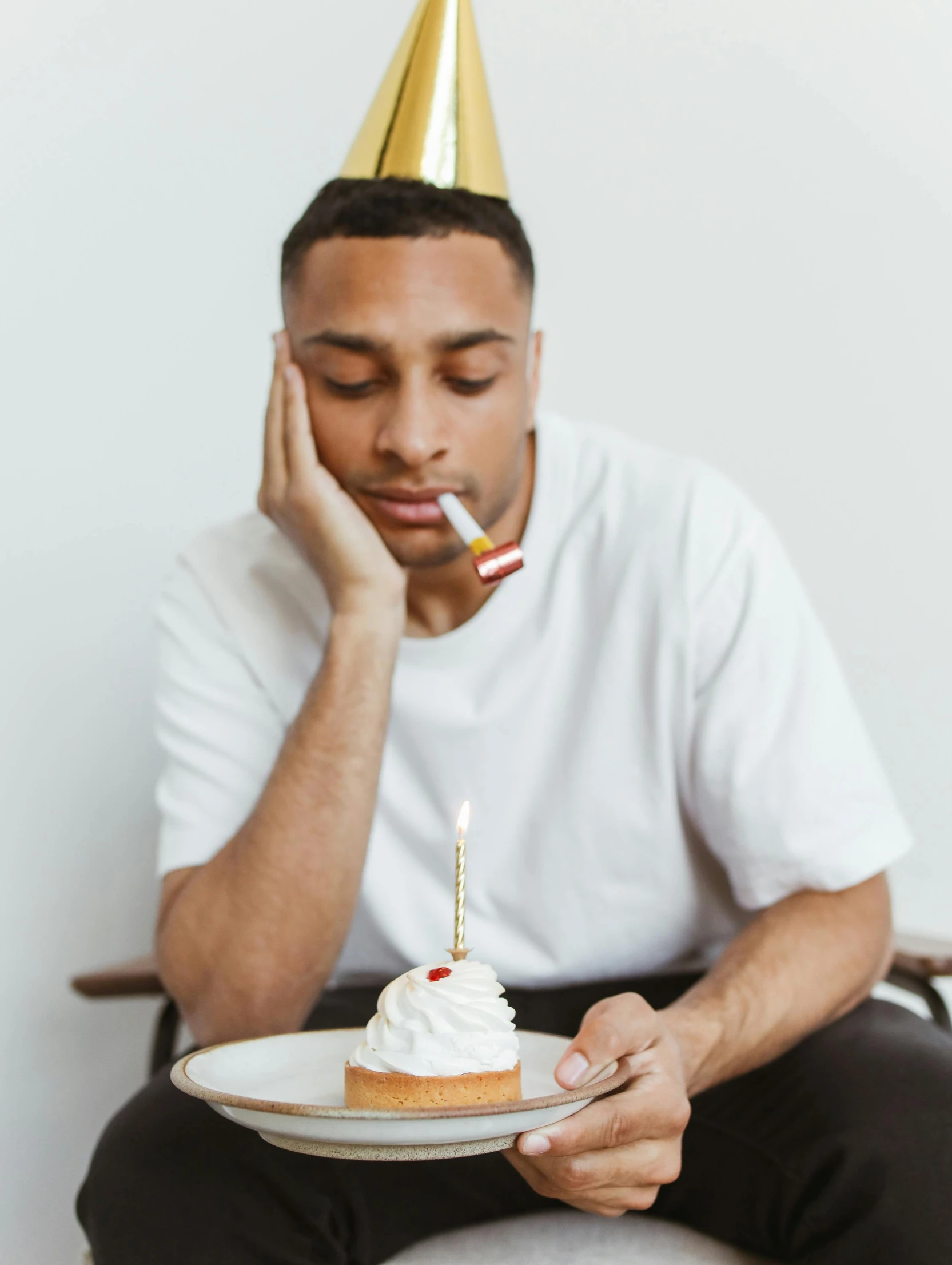 a man sitting on a chair holding a plate with a cake on it, trending on unsplash, hyperrealism, wearing a party hat, sleepy, lean man with light tan skin, man is with black skin