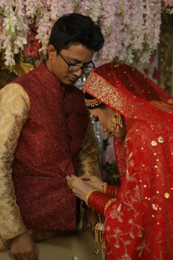 a man standing next to a woman in a red dress, pexels, hurufiyya, bangladesh, rings, bride and groom, praying
