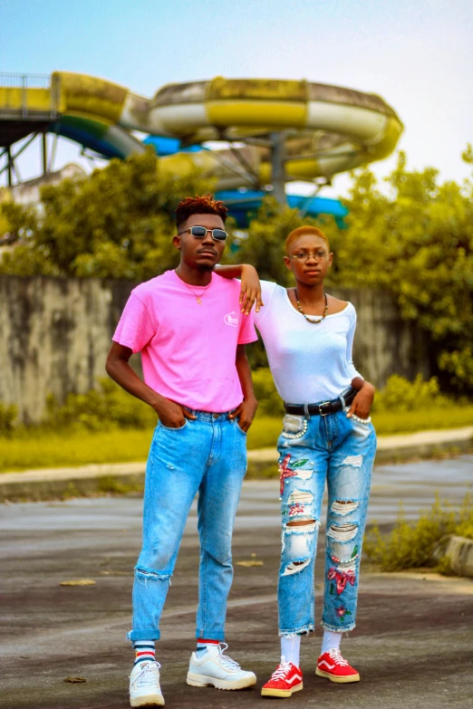 a man and a woman standing in front of a water slide, by Chinwe Chukwuogo-Roy, pexels contest winner, ripped jeans, fully colored, jeans and t shirt, headshot