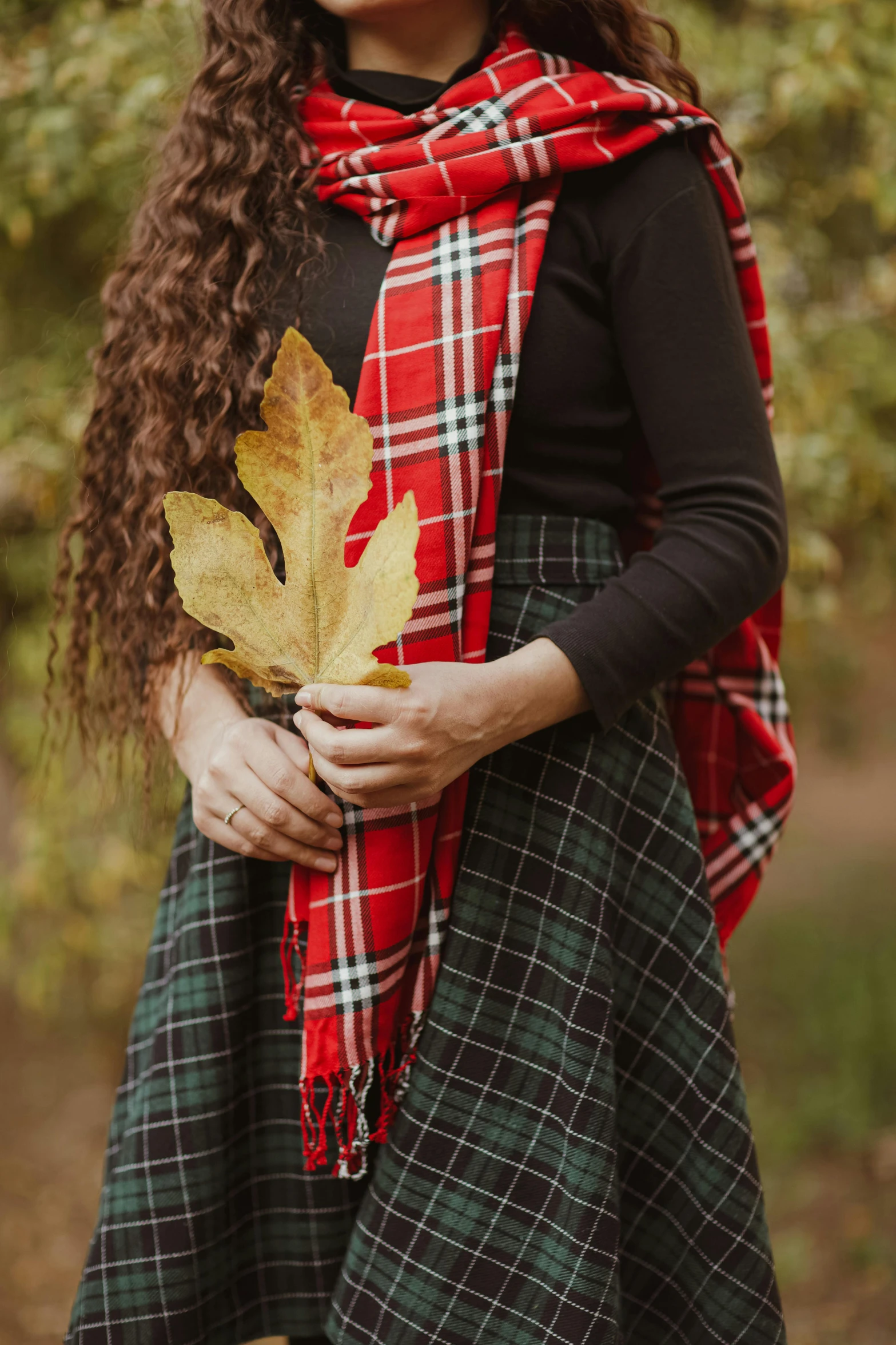 a woman standing in a forest holding a leaf, pexels contest winner, symbolism, plaid skirt, tartan scarf, next to a plant, promo image