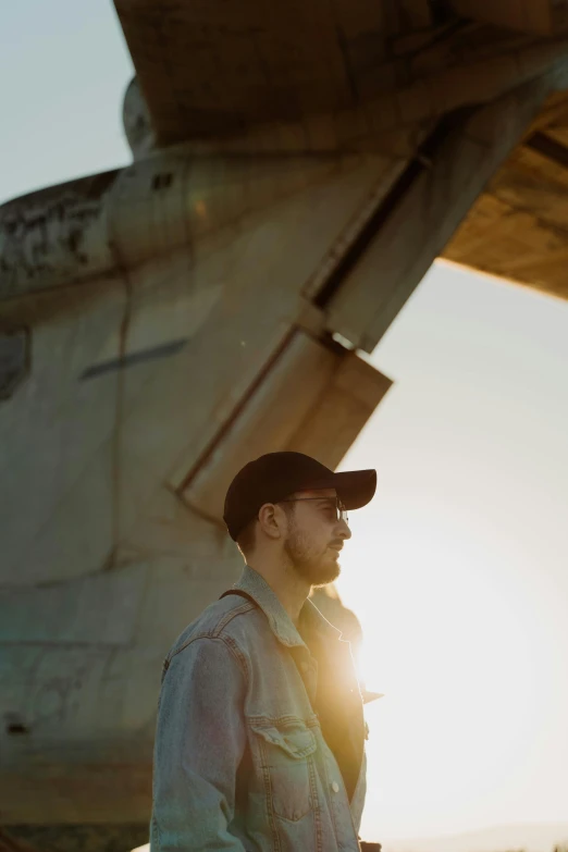 a man standing in front of an airplane, an album cover, pexels contest winner, light and space, low sun, liam, rey, engineer