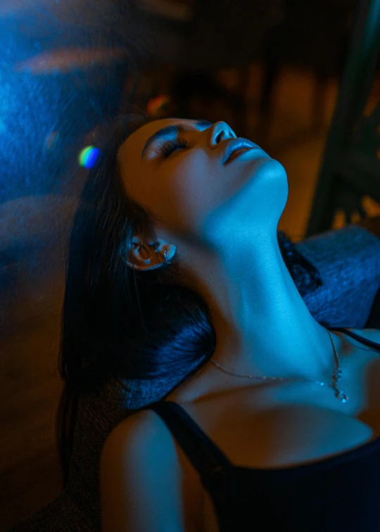 a woman that is laying down in the dark, a portrait, inspired by Elsa Bleda, trending on pexels, holography, cgsociety 8k, jewelry lighting, 8k 28mm cinematic photo, soft calm warm neon atmosphere