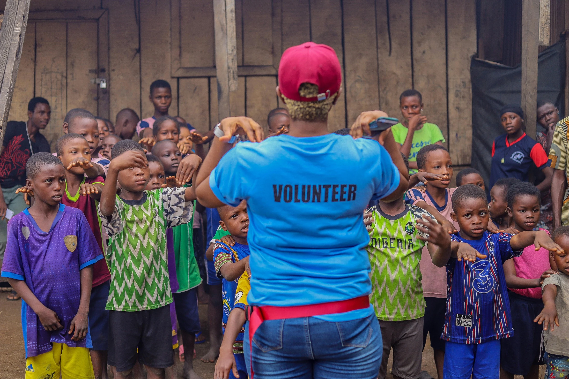 a woman standing in front of a group of children, pexels contest winner, happening, epic 3 d omolu, red and blue garments, health supporter, reaching out to each other