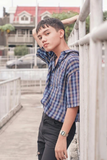 a young man leaning against a railing next to a body of water, an album cover, inspired by Eddie Mendoza, trending on pexels, wearing plaid shirt, pixie cut with shaved side hair, attractive androgynous humanoid, in style of lam manh