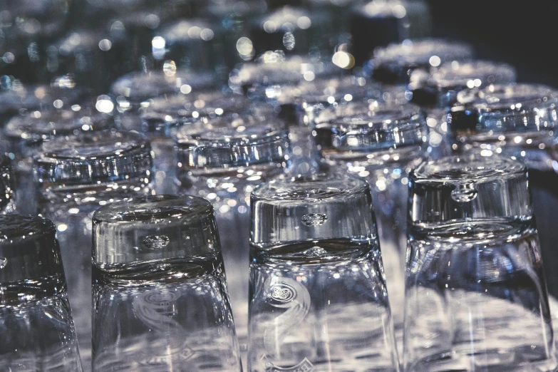 a bunch of empty glasses sitting on top of a table, filled with water, up-close, glassware, water bottles