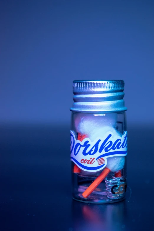 a jar filled with toothbrushes sitting on top of a table, an album cover, by Odhise Paskali, unsplash, photorealism, bubble gum, dark blue neon light, norilsk, miniature model