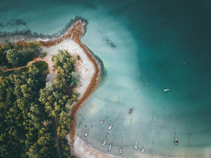 a group of boats floating on top of a body of water, by Adam Marczyński, pexels contest winner, hurufiyya, on an island, close-up from above, thumbnail, manly