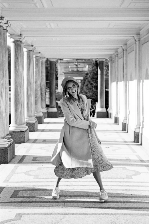 a black and white photo of a woman talking on a cell phone, jessica alba woman, twirling, straw hat and overcoat, on a marble pedestal