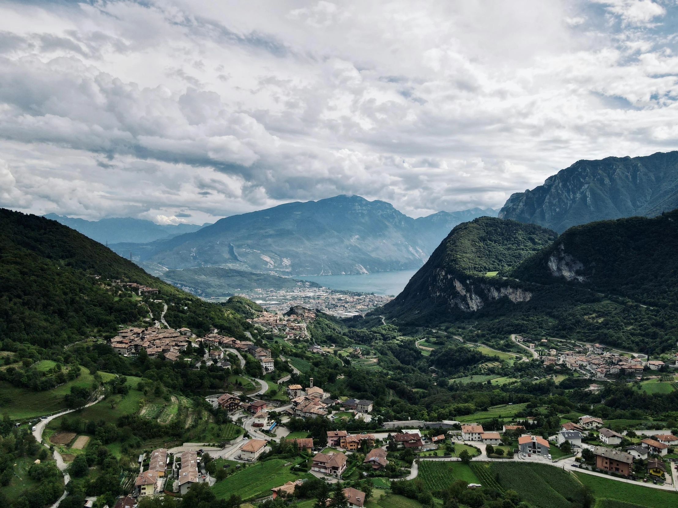 an aerial view of a small town in the mountains, by Alessandro Allori, pexels contest winner, renaissance, grey cloudy skies, green valley below, lake view, 4k footage