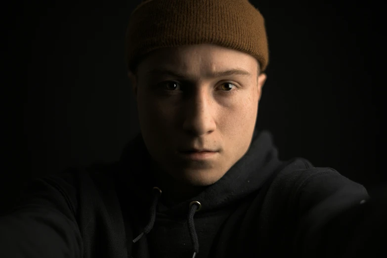 a close up of a person wearing a hat, a character portrait, by Adam Marczyński, unsplash, digital art, male teenager, shot at dark with studio lights, 8k selfie photograph, he is wearing a brown sweater