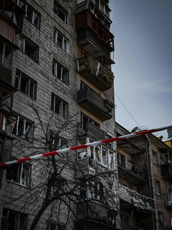 a red and white traffic light sitting in front of a tall building, by Adam Marczyński, pexels contest winner, graffiti, with wires and bandages, war in ukraine, apartment complex made of tubes, 000 — википедия