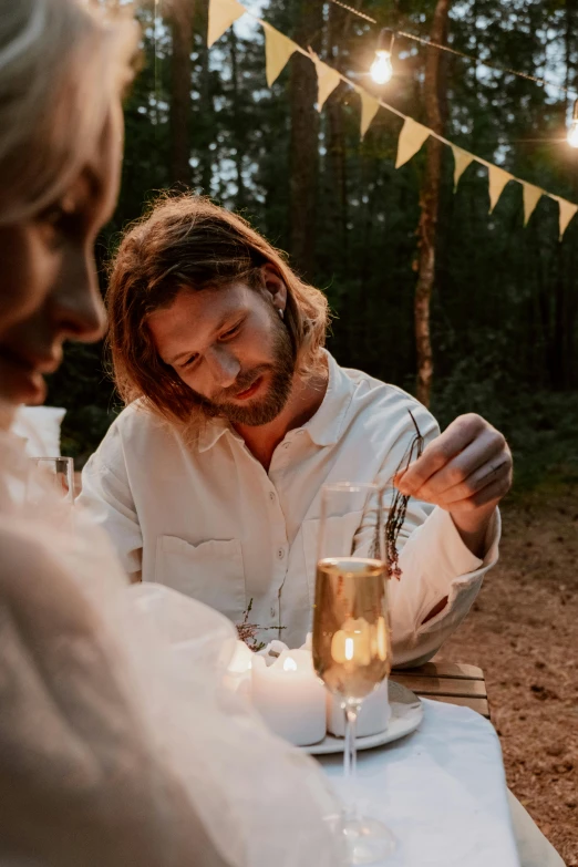 a man and a woman sitting at a table, by Lee Loughridge, pexels contest winner, romanticism, glamping, champagne, wearing a linen shirt, light glow