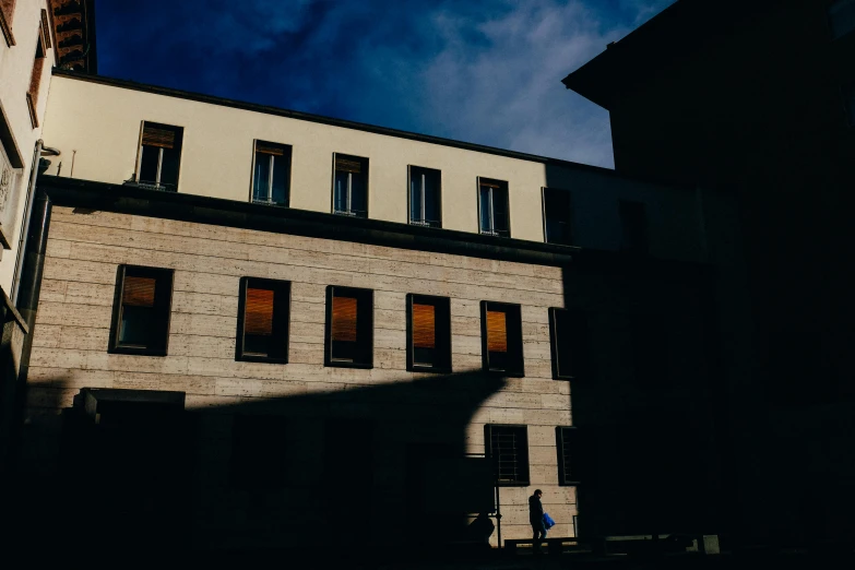 a person sitting on a bench in front of a building, by Tobias Stimmer, back light contrast, low quality photo, high quality image, multiple stories