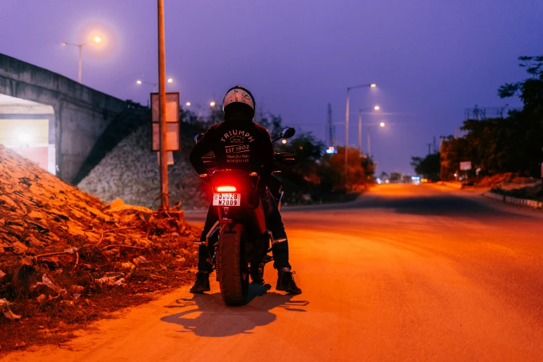 a man riding on the back of a motorcycle down a street, by Kristian Zahrtmann, pexels contest winner, red leds, avatar image, evening time, profile image