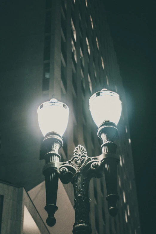 a street light in front of a tall building, by Ryan Pancoast, unsplash contest winner, baroque, headlights, gas lamps, faded glow, gothic lighting