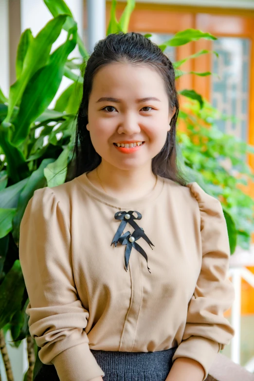 a young girl sitting in front of a potted plant, dang my linh, headshot profile picture, wearing a blouse, welcoming smile