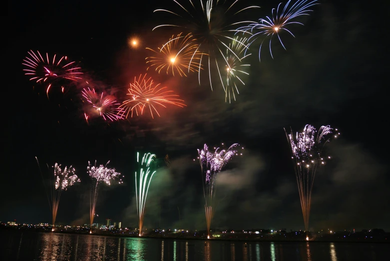 fireworks light up the night sky over a body of water, pexels contest winner, hurufiyya, various colors, manila, composite, 2 5 6 x 2 5 6 pixels