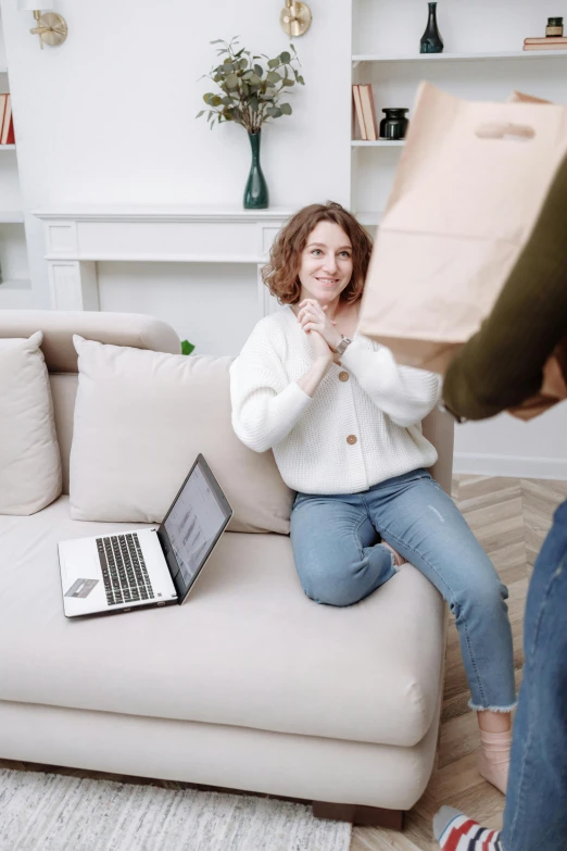 a woman sitting on a couch holding a box, pexels contest winner, happening, exiting store, in front of a computer, wearing a white sweater, flirting